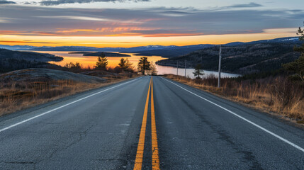 Fototapeta premium Open Road to Sunset: A scenic highway winds through a picturesque landscape, leading towards a breathtaking sunset over a vast lake with a mountain range in the distance, evoking a sense of adventure 