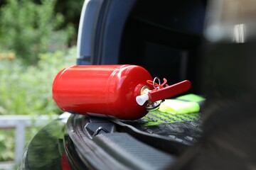 Naklejka premium Red fire extinguisher in trunk. Car safety equipment