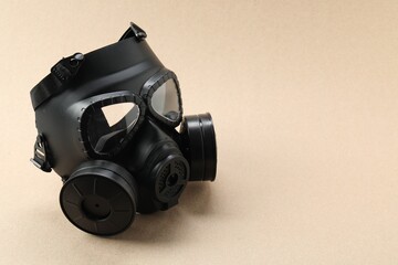 One gas mask on beige background, space for text. Safety equipment