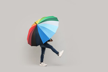 Little girl with colorful umbrella on light grey background