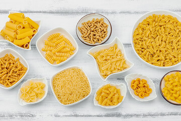 Pasta. Various kinds of uncooked pasta and noodles over wooden background