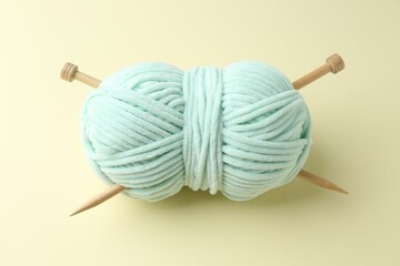 Skein of plush yarn with knitting needles on beige background, above view