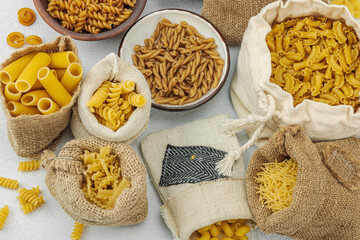 Pasta. Various kinds of uncooked pasta and noodles over light stone background. Traditional Italian