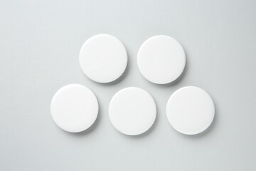 Blank white button badges on light background, flat lay. Mockup for design