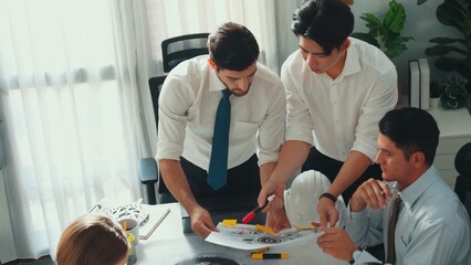 Top view of engineer pointing at turbine engine at meeting table with equipment. Aerial view of professional project manager talking and discussing about electronic generator system. Alimentation.
