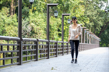 Young woman jogging and listening to music at the park.