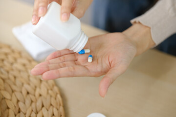 A person is taking a pill from a white bottle