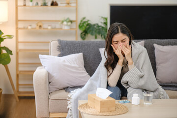A woman is sitting on a couch with a tissue box next to her