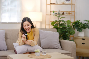 A woman is sitting on a couch with a phone in her hand