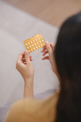 A woman is holding a pack of birth control pills