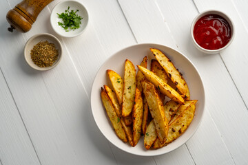 Air Fryer Roast Potatoes on white plate,potato wedges with tomatoes sauce.Top view.