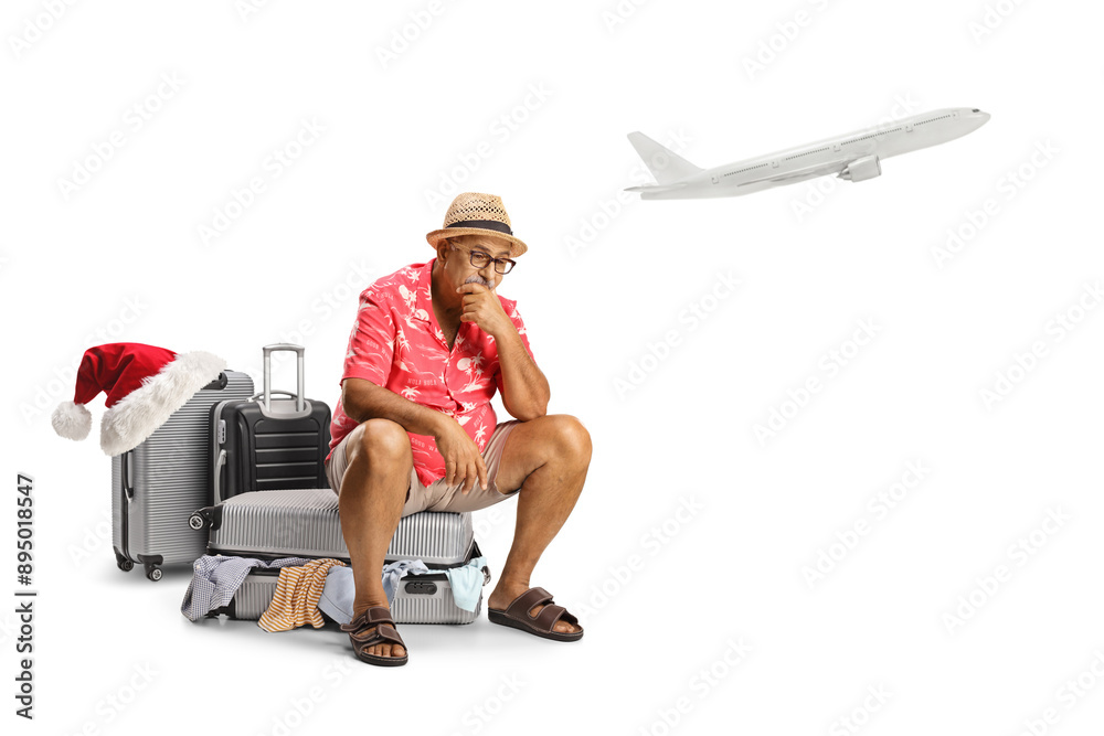 Sticker Sad mature man waiting for a christmas flight and sitting on a packed suitcase