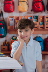 Kind in school first dat of school on a desk and holding am apple backpacks and classroom 