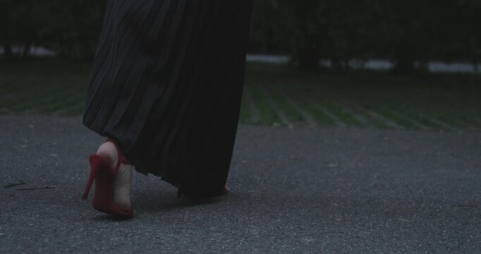 woman in red heels and black dress walks