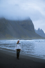 young woman walks on a black beach in Iceland