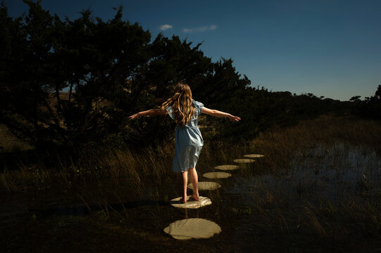 Young girl walking down stone path through flooded field