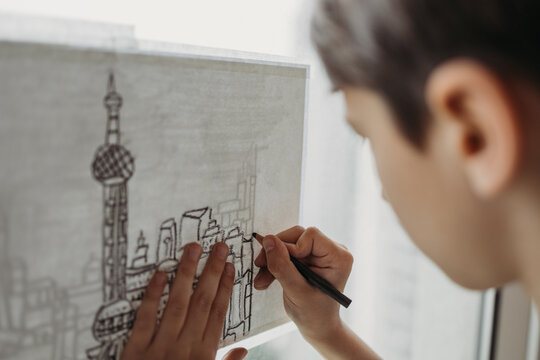 Close up view of the boy drawing the city on the window
