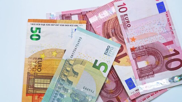 Falling euros banknotes and pile of euro currency banknotes are spinning on table