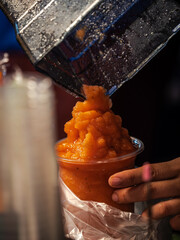 orange smoothie is poured from a blender into the cup.