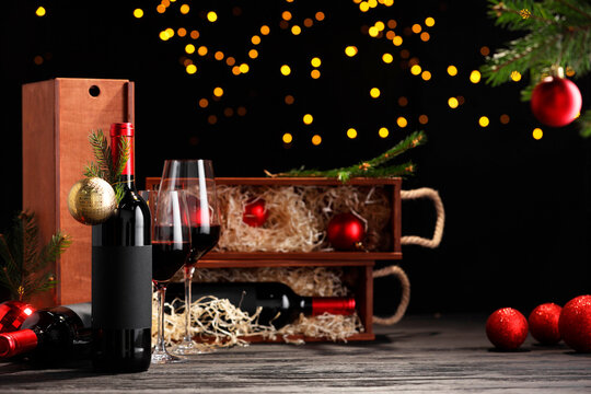 Bottles of wine, glasses, wooden boxes, fir twigs and Christmas balls on table