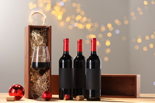 Bottles of wine, glass, wooden gift boxes, corks and red Christmas balls on table - Powered by Adobe
