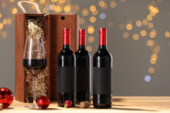 Bottles of wine, glass, wooden gift boxes, corks and red Christmas balls on table