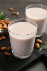 Glasses of almond milk and almonds on grey table