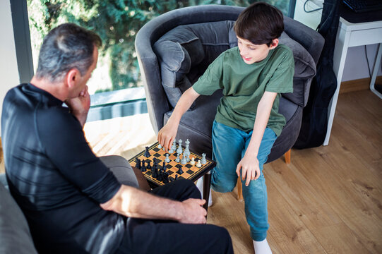 Father and son playing chess at home