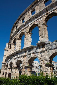 View through the stone structure of the ancient Roman Amphitheater, the Pula Arena with a blue sky, constructed in 27 BC - AD 68; Pula, Croatia