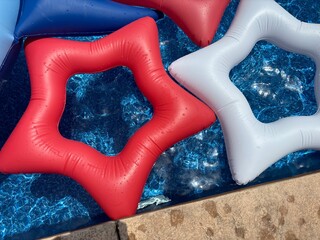 Colorful star-shaped pool floats in blue water on a sunny day