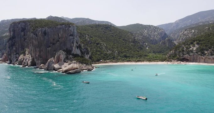 Boats At Cala Sistine, Beautiful Beach With Cliffs On Coast Of Sardinia.Tracking Aerial Shot.