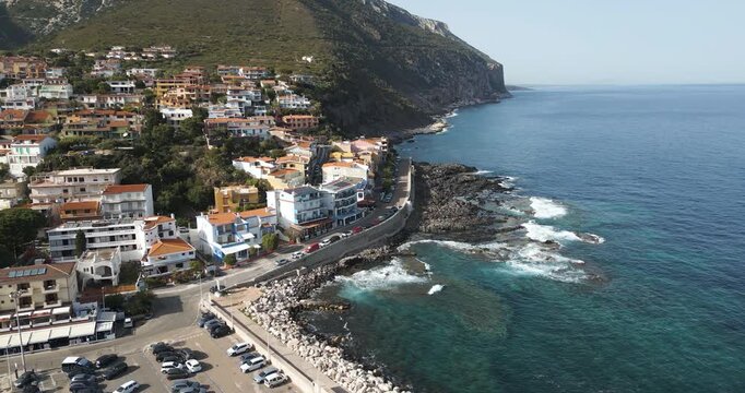 Cala Gonone, Gulf of Orosei, Sardinia, Italy - Cars Parked in Front of Vibrant Beachfront Houses - Aerial Drone Shot
