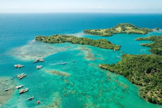 Boats moored in the turquoise waters of Molucca Sea off the coast of Borgo Satu in North Sulawesi, Indonesia; Borgo Satu, Belang, Southeast Minahasa Regency, North Sulawesi, Indonesia
