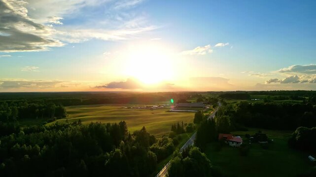 Landscape pan of beautiful early morning sunrise on horizon with rays bursting through clouds in sky scenery nature outdoors countryside farm acreage rural town