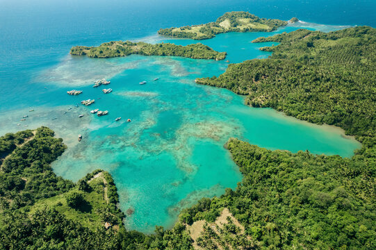 Boats moored in the turquoise waters of Molucca Sea off the coast of Borgo Satu in North Sulawesi, Indonesia; Borgo Satu, Belang, Southeast Minahasa Regency, North Sulawesi, Indonesia