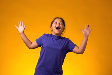 Scared little girl over yellow background, child watching horror film, movie, reaction, facial expression.