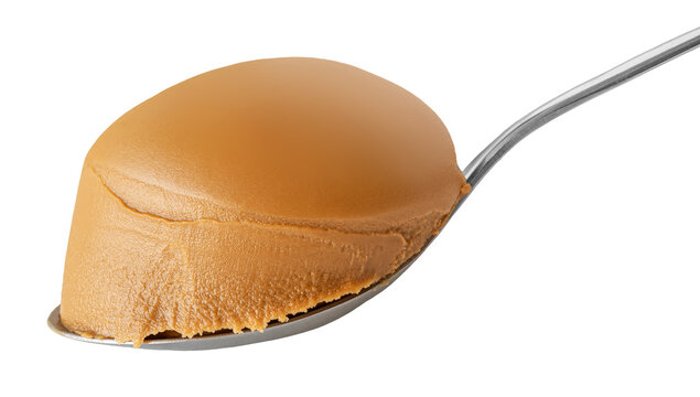 Peanut butter in spoon isolated on white background. Creamy peanut buter swirl closeup.