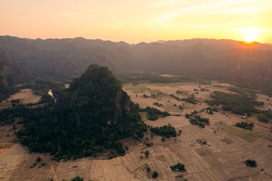 Golden sunset light over farmland in a valley surrounded by limestone karst near Kong Lor Cave in Laos; Khammouane Province, Laos
