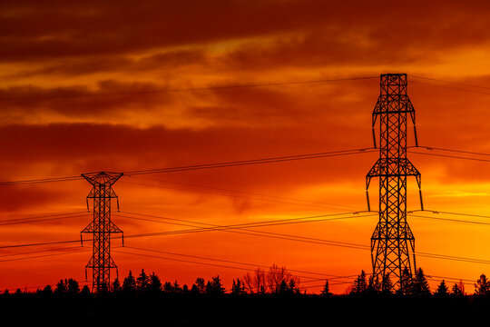 Silhouette of large metal electrical towers with a colourful dramatic sky in the background; Calgary, Alberta, Canada