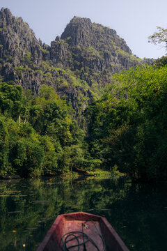 Bow of a boat as it travels through the tranquil water of Nam Hin Bun River at Kong Lor Cave in Phu Hin Bun National Park, Laos; Khammouane Province, Laos