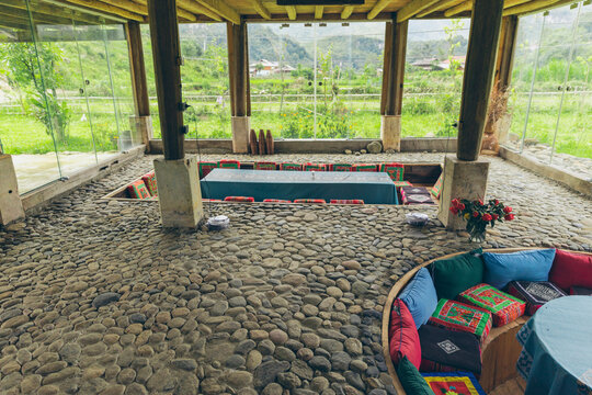 Sunken seating areas with colourful cushions inside a room with glass walls giving natural light; Ngoc Chien, Muong La District, Son La, Vietnam