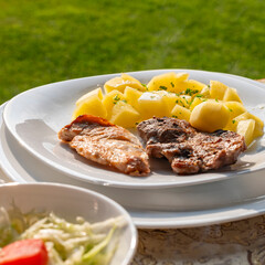 simple and tasty menu, natural potatoes soaked in butter and flavored with parsley and barbecued pork, at a garden party in a summer afternoon
