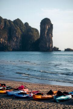 Kayaks in a row on Ao Nang Beach with blue ocean water and rugged cliffs along the coastline, Krabi, Thailand; Krabi, Thailand