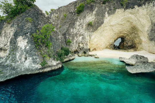 White sand beach with natural arch along a rugged coastline in the Molucca Sea, in Central Sulawesi, Indonesia; Tanjung Gundul Pasir Putih, Banggai Islands Regency, Central Sulawesi, Indonesia
