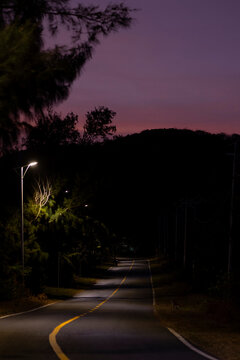 Street lights illuminate a street at night with a slight glow in the sky; Bai Nhat, Con Dao, Vietnam