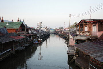 Traditional Thai riverside houses along a calm canal in Thailand during sunset, reflecting local culture, architecture, and peaceful waterfront lifestyle.