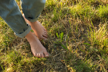 Woman walking barefoot on green grass outdoors, closeup. Space for text