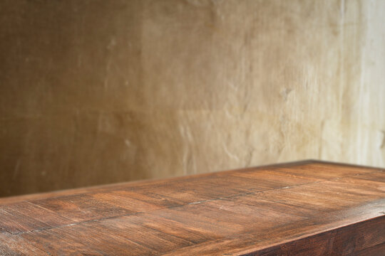 Dark wooden table top with empty copy space and gold structured textured wall backround.