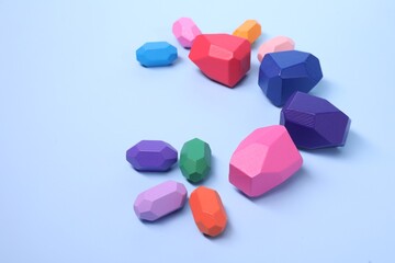 Many colorful balancing stones on light blue background, space for text