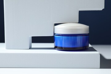 Stylish presentation of face cream in jar against blue background